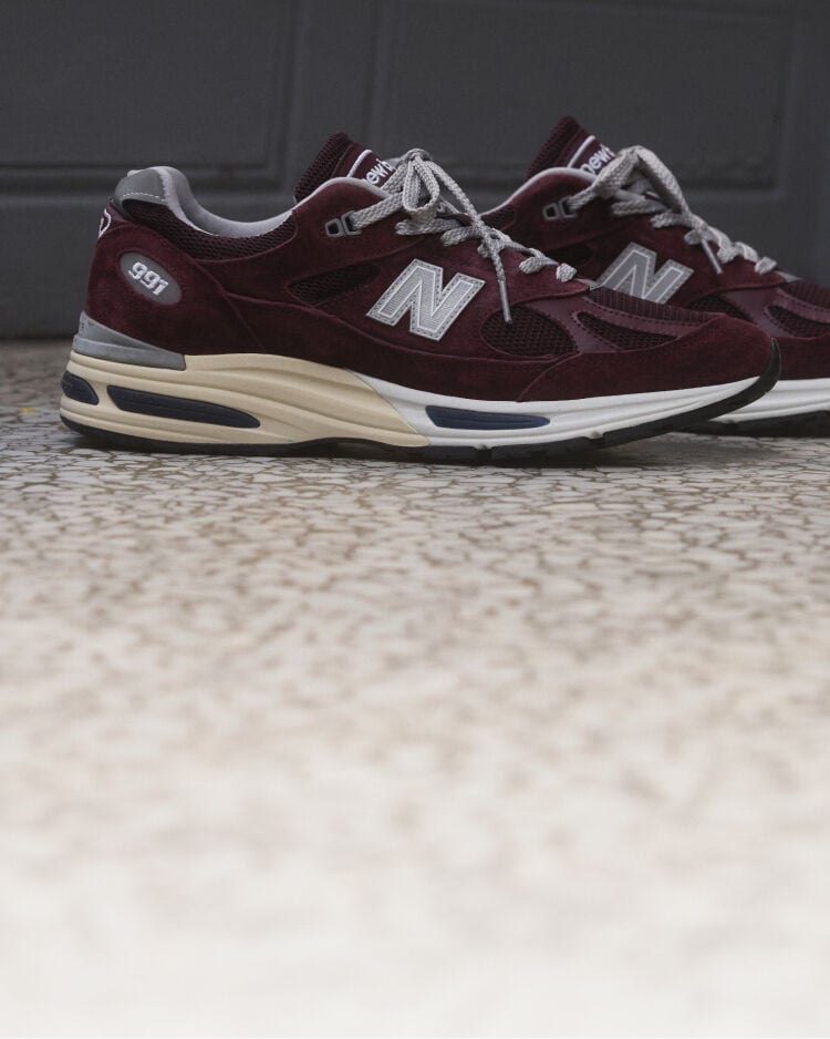 A pair of New Balance Made in UK sneakers sitting on a concrete floor.