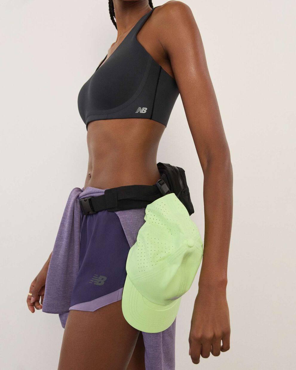 A woman wearing New Balance standing in front a white wall.