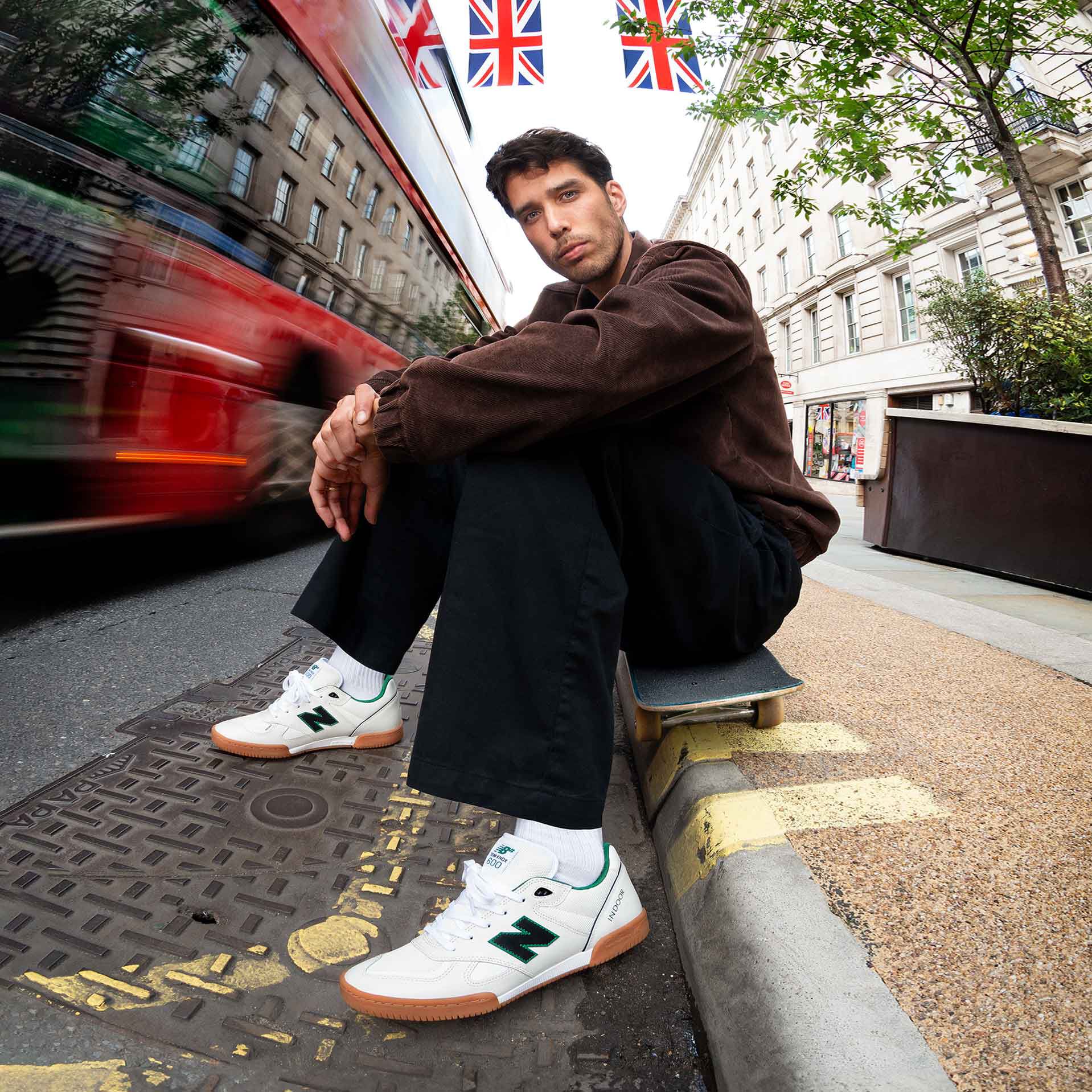 Tom Knox sitting on a curb outside wearing white Numeric 600 shoes.