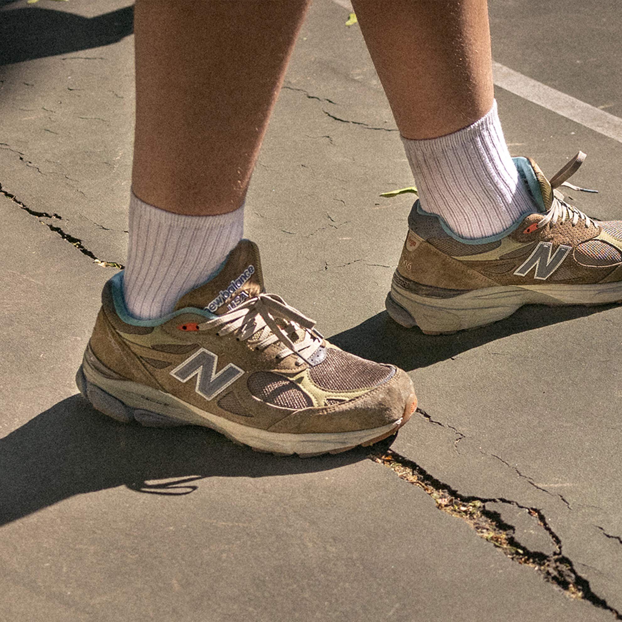 Young male walking on street wearing pair of 990v3 shoes