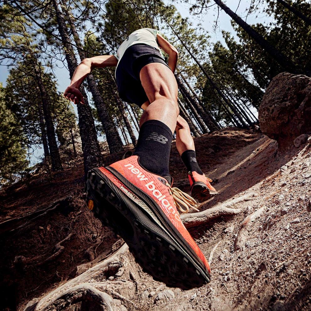 A trail runner running uphill with the New Balance FuelCell SuperComp Trail shoes