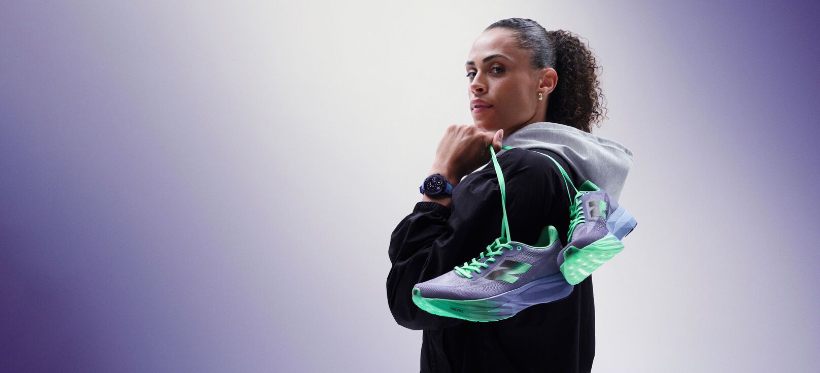 Sydney McLaughlin-Levrone holding a pair of shoes over her shoulder and looking towards the viewer. 