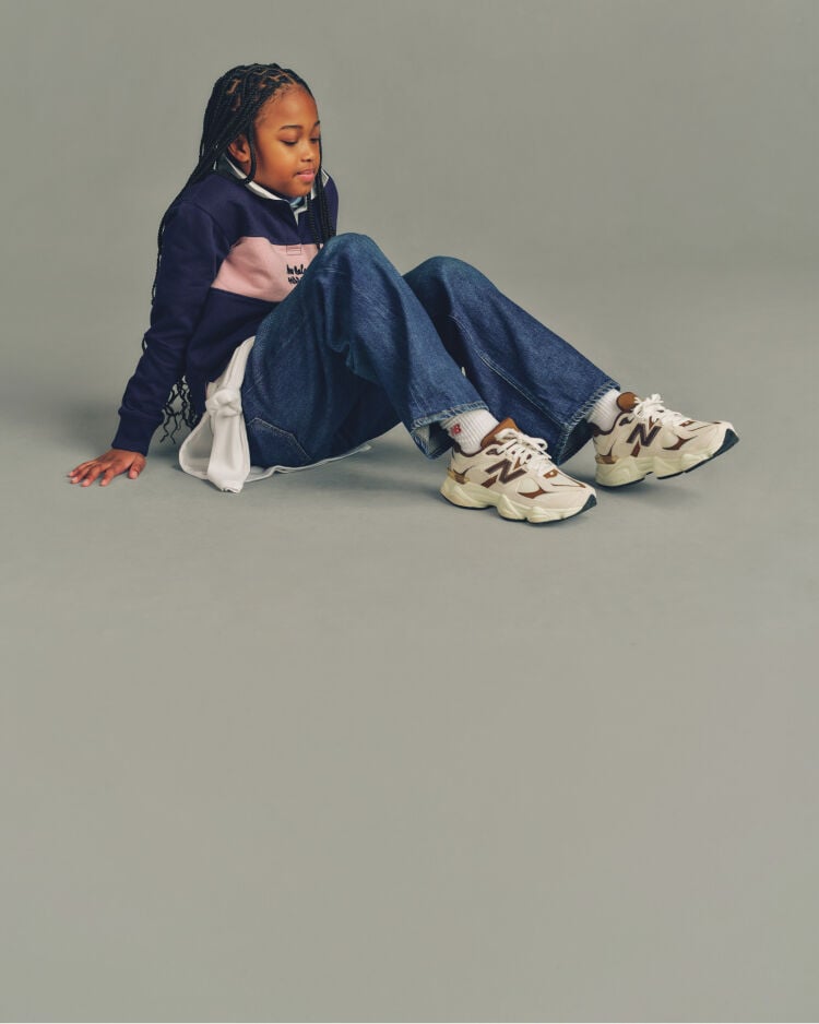 Child sitting on the ground wearing New Balance